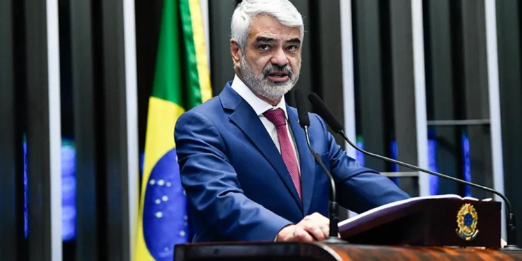 Senador Humberto Costa discursando no plenário do Senado, com a bandeira do Brasil ao fundo.