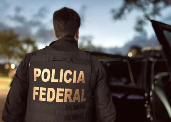 Agente da Polícia Federal durante operação ao anoitecer.