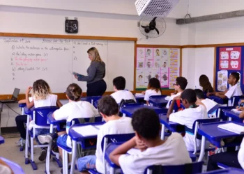 Alunos do ensino fundamental em aula de inglês com professora no quadro.