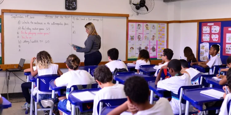 Alunos do ensino fundamental em aula de inglês com professora no quadro.