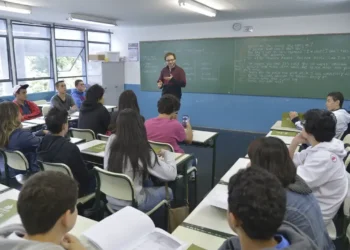 Alunos acompanham aula de inglês com professor utilizando a lousa em escola pública de São Paulo.