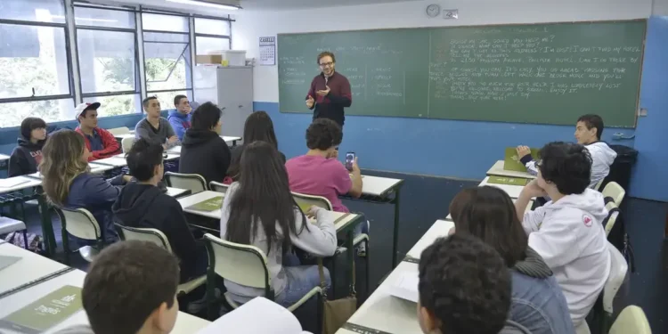 Alunos acompanham aula de inglês com professor utilizando a lousa em escola pública de São Paulo.