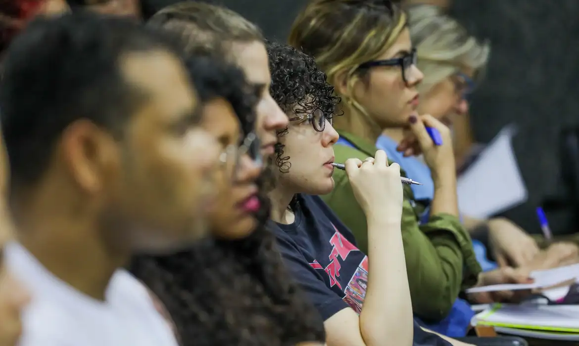 Candidatos concentrados durante aula preparatória para concursos públicos.