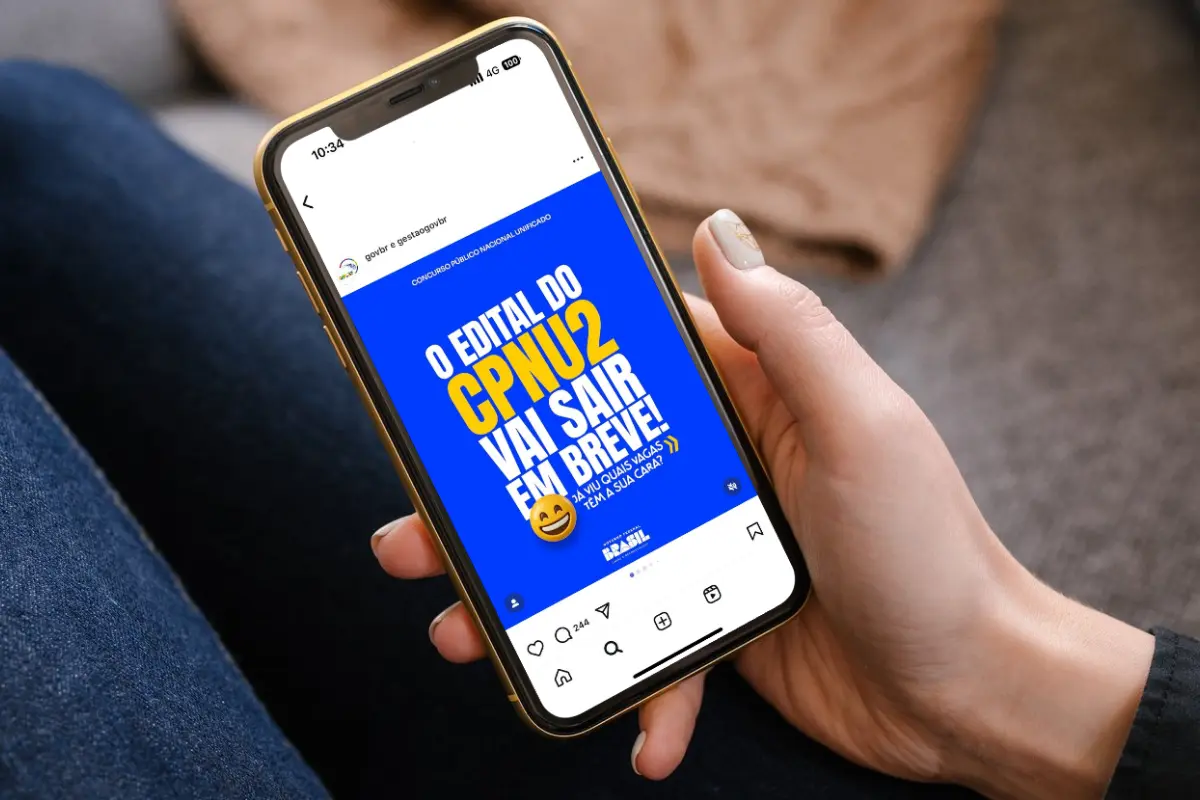 Pessoa segurando celular com anúncio sobre o edital do CPNU2 nas redes sociais do governo federal.
