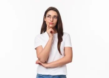Jovem com expressão pensativa, usando óculos e camiseta branca.