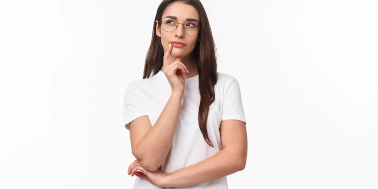 Jovem com expressão pensativa, usando óculos e camiseta branca.