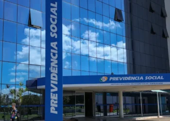 Fachada do prédio da Previdência Social com reflexo do céu azul.