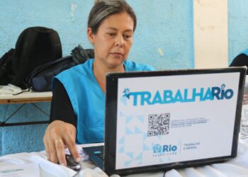 Profissional utilizando computador em uma feira de emprego, no estado do Rio de Janeiro, buscando oportunidades de trabalho.