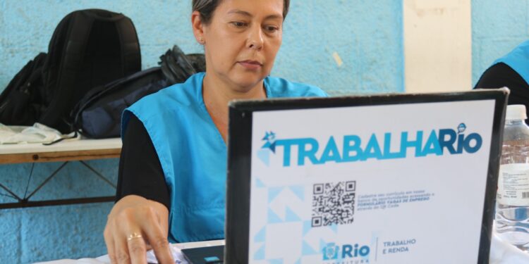 Profissional utilizando computador em uma feira de emprego, no estado do Rio de Janeiro, buscando oportunidades de trabalho.
