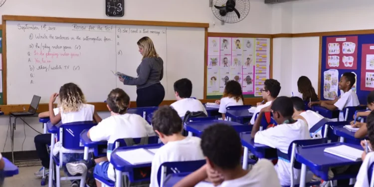 Professora ministra aula de inglês para turma do ensino fundamental.