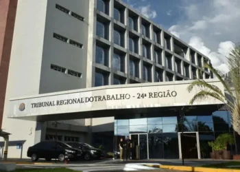 Fachada do Tribunal Regional do Trabalho da 24ª Região, mostrando o prédio e os carros estacionados na entrada, simbolizando a anulação do Concurso do TRT-MS