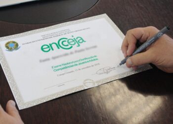 Certificado de conclusão do Encceja sendo assinado com caneta.