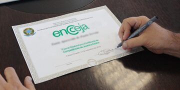 Certificado de conclusão do Encceja sendo assinado com caneta.