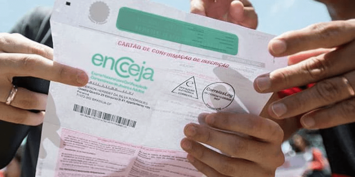 Pessoa segurando o cartão de confirmação de inscrição do Encceja. 