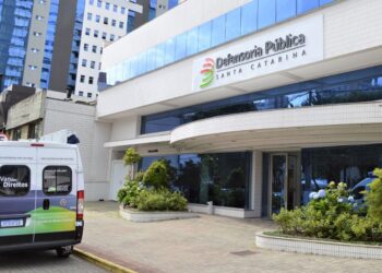 Fachada do concurso Defensoria Pública de Santa Catarina, com um veículo da instituição estacionado em frente ao prédio.