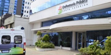 Fachada do concurso Defensoria Pública de Santa Catarina, com um veículo da instituição estacionado em frente ao prédio.