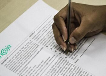 Mão segurando uma caneta, preenchendo uma prova. O resultado do Encceja 2025 sai em dezembro.