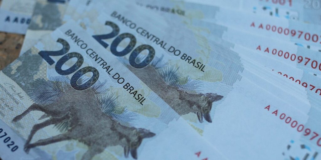 Notas de duzentos reais empilhadas evidenciando design com lobo-guará e elementos de segurança