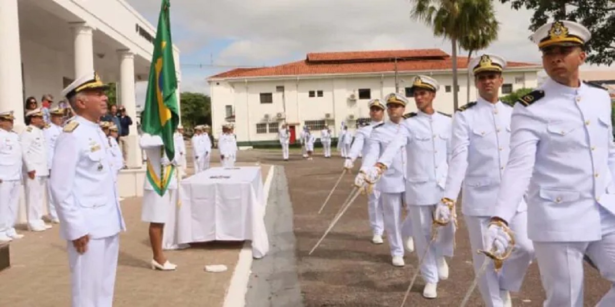 Oficiais da Marinha do Brasil em uniforme branco participando de cerimônia formal ao ar livre
