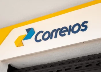 Fachada de agência dos Correios com o logotipo da empresa em amarelo e azul.