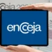 Tablete com a logo do Encceja, sendo exibido acima de uma folha de redação e o nome do exame, representando a importância do estudo digital e da prova para a certificação.