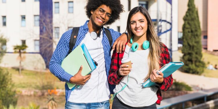 Dois estudantes sorrindo e segurando livros, simbolizando as oportunidades de estágio e bolsa de estudo no TRT-15 para universitários.