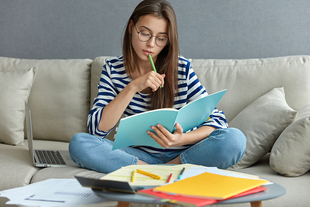 Mulher jovem estudando e fazendo anotações enquanto se prepara para concursos públicos.