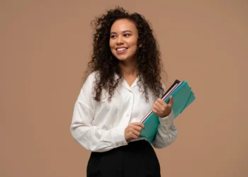 Jovem aprendiz com TEA segurando pastas coloridas, com inscrições para o programa Bradesco até 26/09