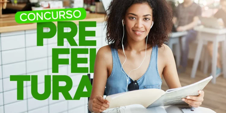 Mulher jovem estudando e sorrindo enquanto ouve música, com fones de ouvido, ao lado de uma mesa com materiais de concurso, com destaque para o concurso da Prefeitura de Joanópolis.