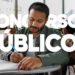 Homem concentrado escrevendo em folha dentro de biblioteca para provas de concursos públicos