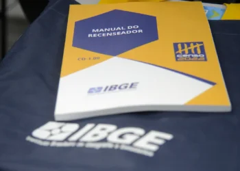 Manual do recenseador do Censo do IBGE sobre bolsa azul com logo do IBGE