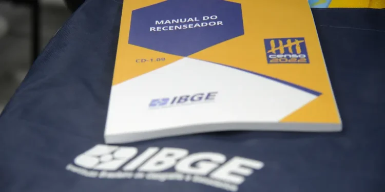 Manual do recenseador do Censo do IBGE sobre bolsa azul com logo do IBGE