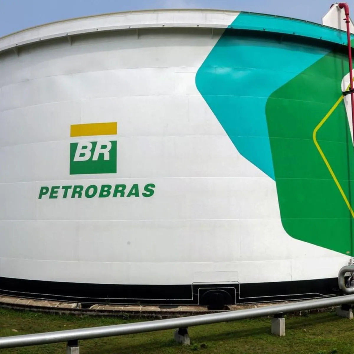 Bandeira branca da Petrobras e bandeira do Brasil lado a lado em mastro com fundo de estrutura metálica e vidro