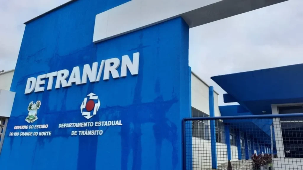 Fachada DETRAN RN: Concurso Público com 80 Vagas Mais Próximo Fachada moderna da sede do DETRAN/RN (Departamento Estadual de Trânsito do Rio Grande do Norte), em azul vibrante, representando a abertura iminente do concurso público com 80 vagas.
