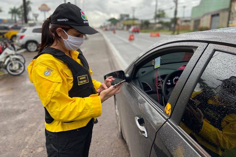 Agente de fiscalização do DETRAN utilizando celular durante abordagem a veículo.