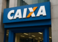 Fachada de agência da Caixa Econômica Federal com logo branco, azul e laranja em destaque