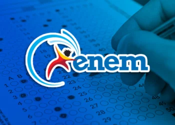 Mão preenchendo gabarito do ENEM com caneta em folha azul, com logo do ENEM.