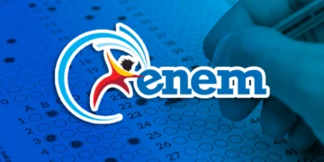 Mão preenchendo gabarito do ENEM com caneta em folha azul, com logo do ENEM.