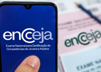 Aplicativo Encceja (Exame Nacional para Certificação de Competências de Jovens e Adultos) em tela de smartphone, com a inscrição oficial sobreposta ao logo em um fundo azul-escuro.