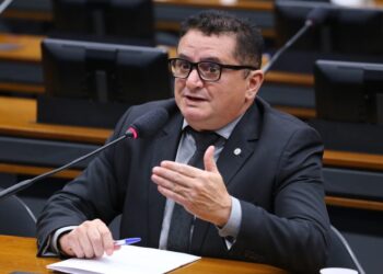 Homem de terno preto e óculos falando em microfone durante sessão na Câmara dos Deputados