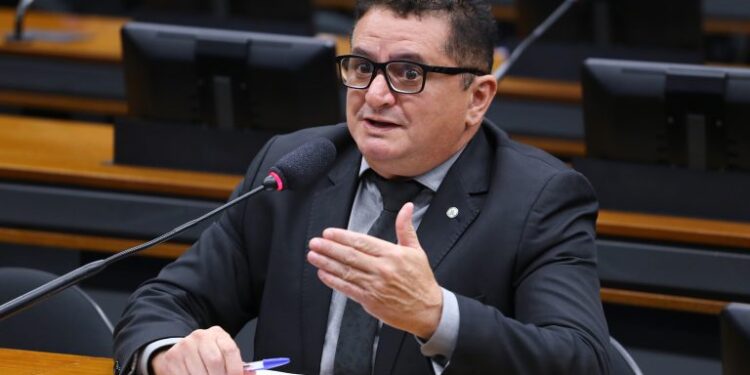 Homem de terno preto e óculos falando em microfone durante sessão na Câmara dos Deputados