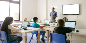 Professor explicando lição para alunos em sala de aula, todos com computadores, abordando conceitos do Sistema Nacional de Educação.