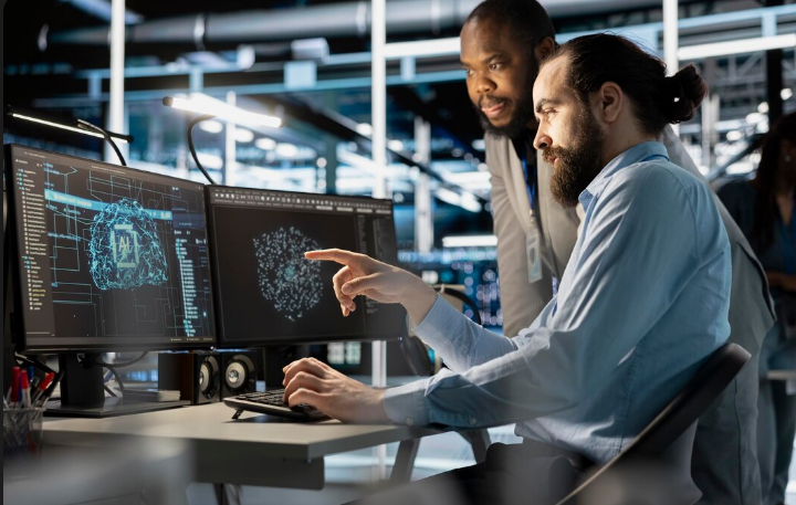 engenheiro inteligencia artificial machine learning carreira Dois especialistas em tecnologia em um escritório moderno analisando um modelo tridimensional de Inteligência Artificial e redes neurais em um monitor de computador.