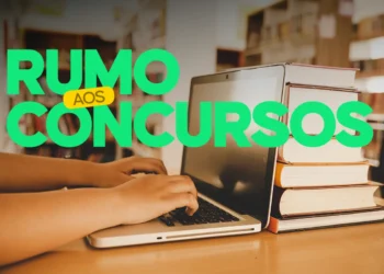 Pessoa digitando em um laptop, com livros ao lado, simbolizando preparação para concursos.