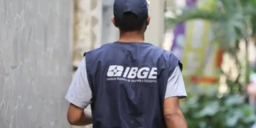 Agente do IBGE com colete institucional caminhando pela rua.