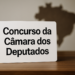 Placa com os dizeres 'Concurso da Câmara dos Deputados' sobre uma mesa.