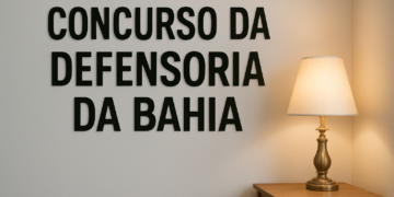 Parede com a frase 'Concurso da Defensoria da Bahia' e um abajur aceso sobre uma mesa