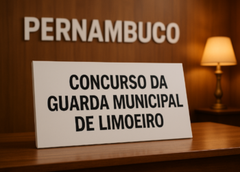 Placa com os dizeres 'Concurso da Guarda Municipal de Limoeiro' sobre uma mesa de madeira.