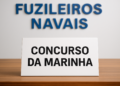 Placa branca com letras pretas escrito "Concurso da Marinha" em mesa de madeira.
