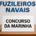 Placa branca com letras pretas escrito "Concurso da Marinha" em mesa de madeira.